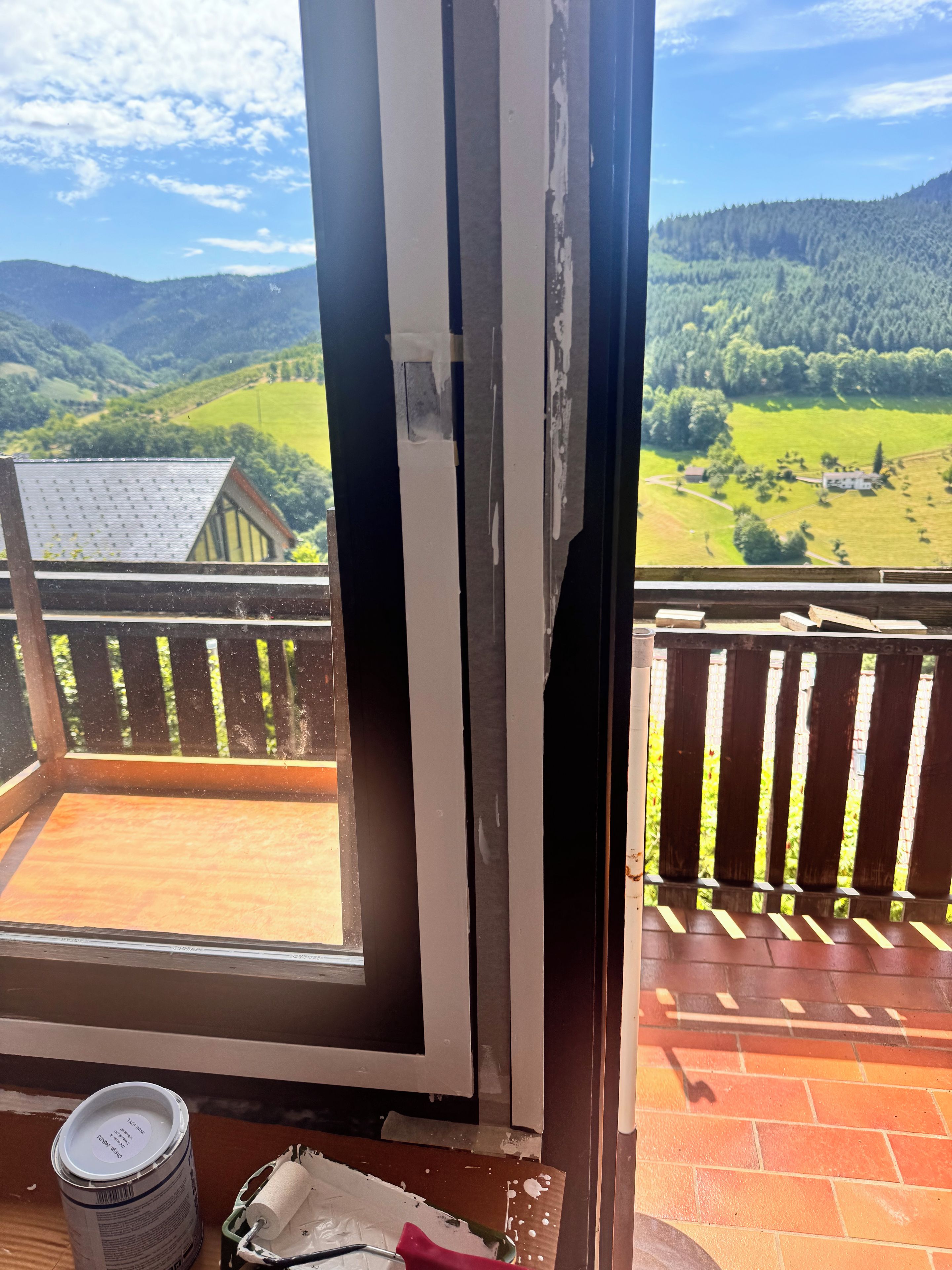 A balcony with a view of green hills and a house.