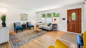 A living room with a sofa, two armchairs, a coffee table, a rug, and a wooden door. - Cozy Pet & Family-friendly fully fenced beautiful  backyard (Arvada)