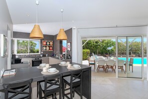 A modern kitchen with a dining area, a poolside seating area, and a view of the outdoors.