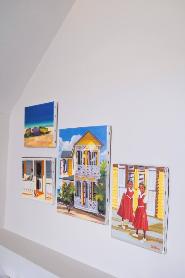Una pared con tres cuadros enmarcados que muestran casas y gente.