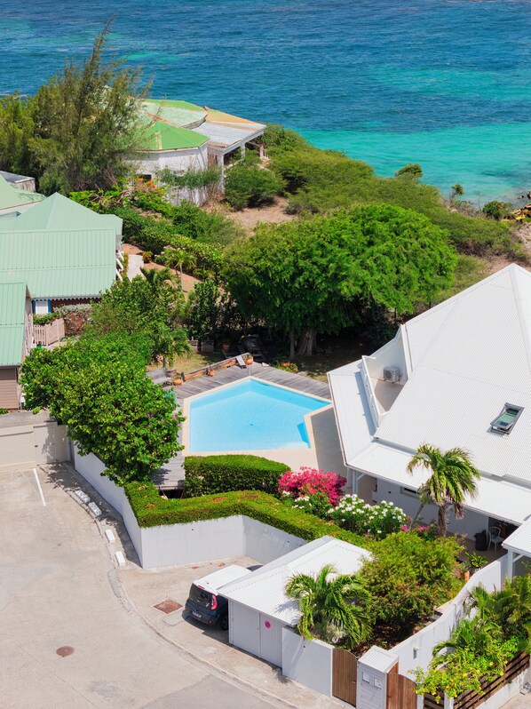 A residential property with a swimming pool, lush greenery, and a view of the ocean. -  VILLA AUX OISEAUX Sea Views & Kayaks (SAINT MARTIN)