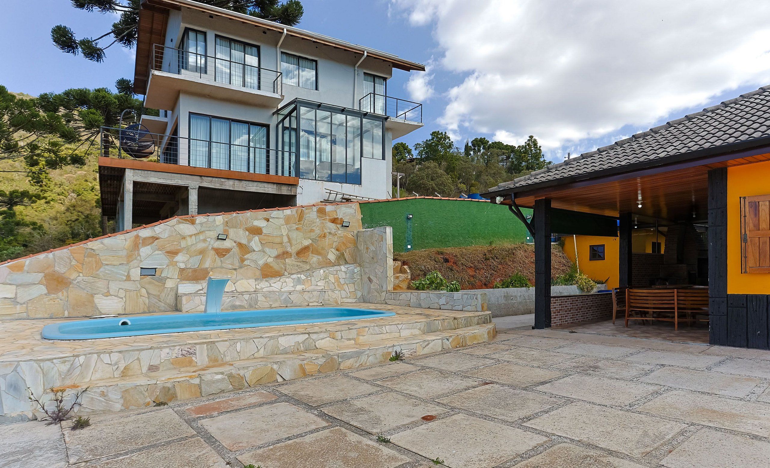 A modern house with a stone pool, a covered patio, and a large glass window.