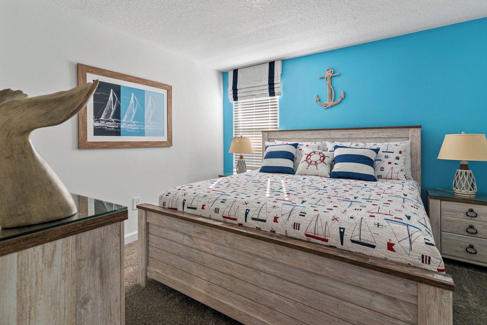 Ein Schlafzimmer mit einem Bett, einem Holz-Kopfteil, einem Nachttisch, einer Lampe, einem gerahmten Bild und einem Wandanker.