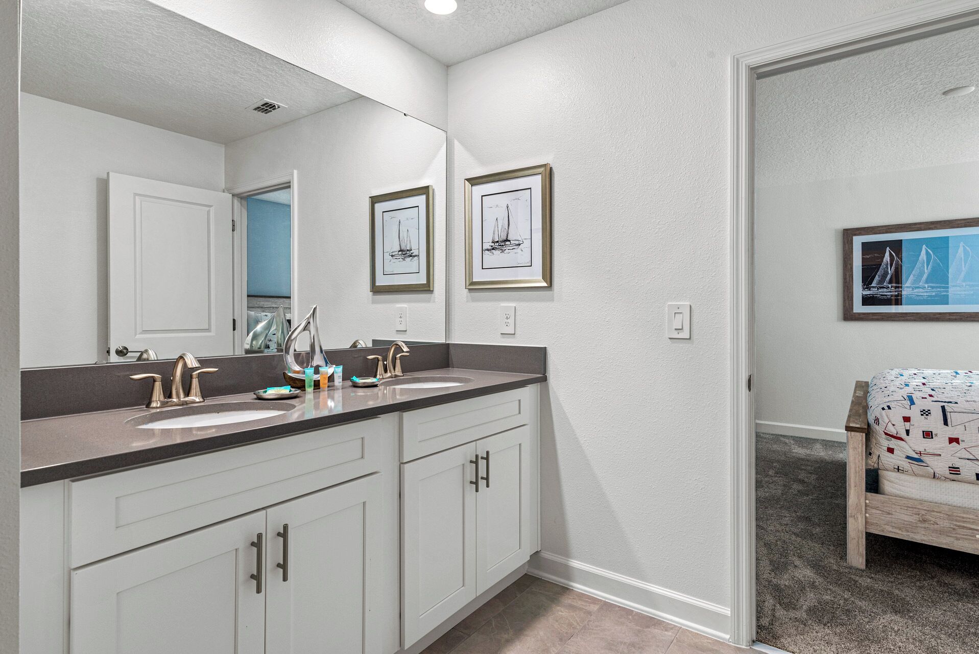 A bathroom with two sinks, a large mirror, and framed artwork on the wall.