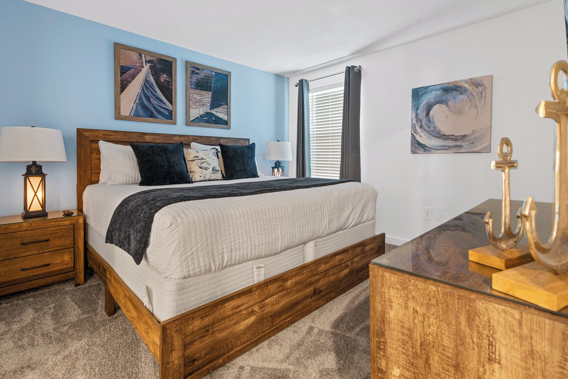 Une chambre à coucher avec un lit en bois, deux tables de chevet, un bureau avec une lampe et des œuvres d’art accrochées aux murs.