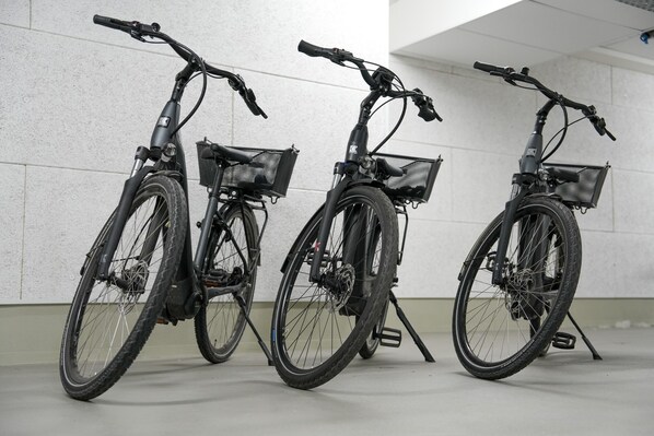 Tres bicicletas estacionadas junto a una pared en una habitación con suelo de baldosas.
