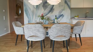 Un comedor con una mesa de madera, cuatro sillas estampadas, un cuadro abstracto grande e iluminación colgante.