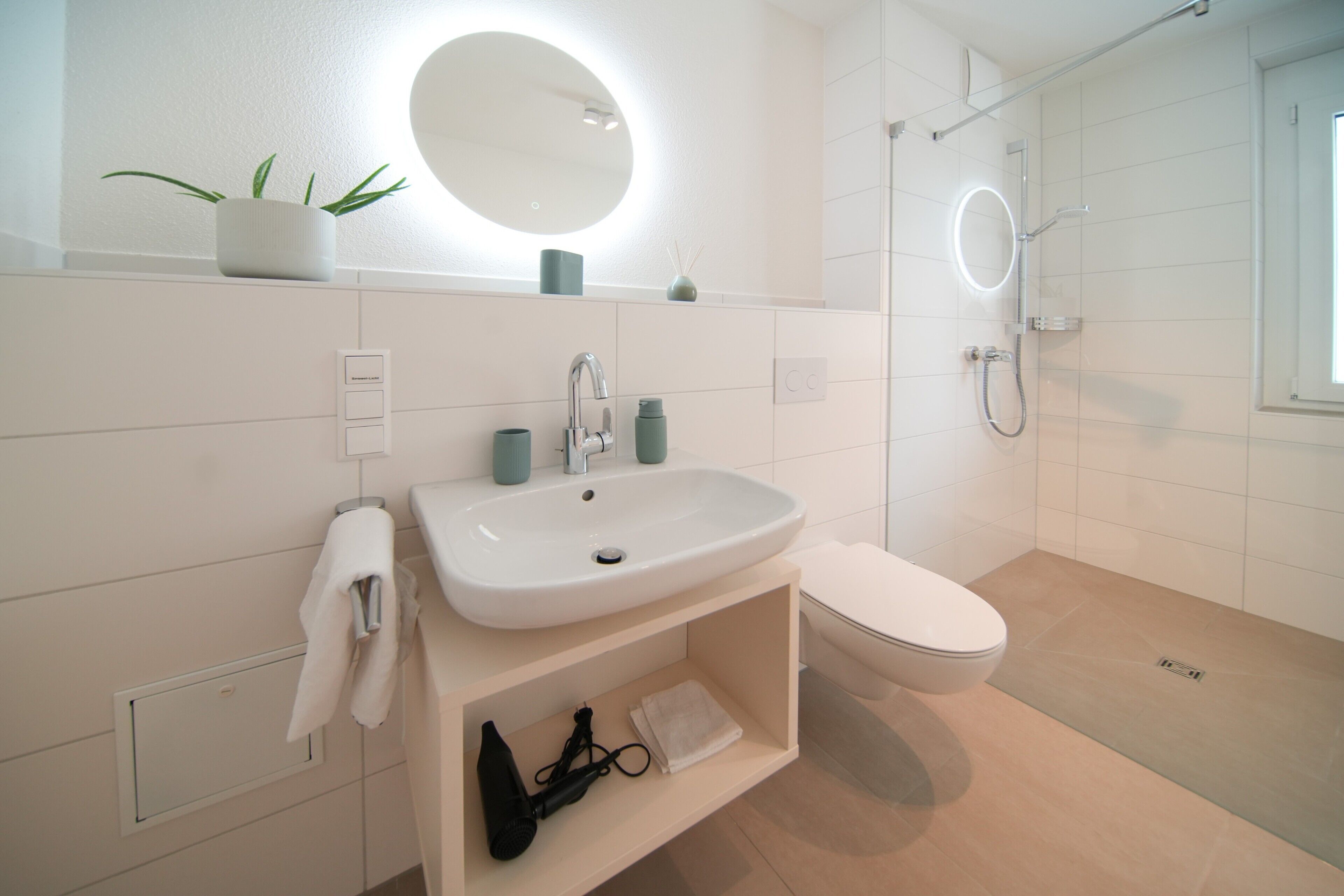 Ein modernes Badezimmer mit Waschbecken, Spiegel, Toilette und Dusche.