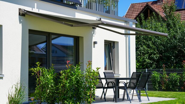 Una casa moderna con un patio, una puerta corrediza de vidrio y un pequeño jardín.