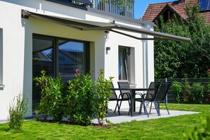 Una casa moderna con un patio, una puerta corrediza de vidrio y un pequeño jardín.