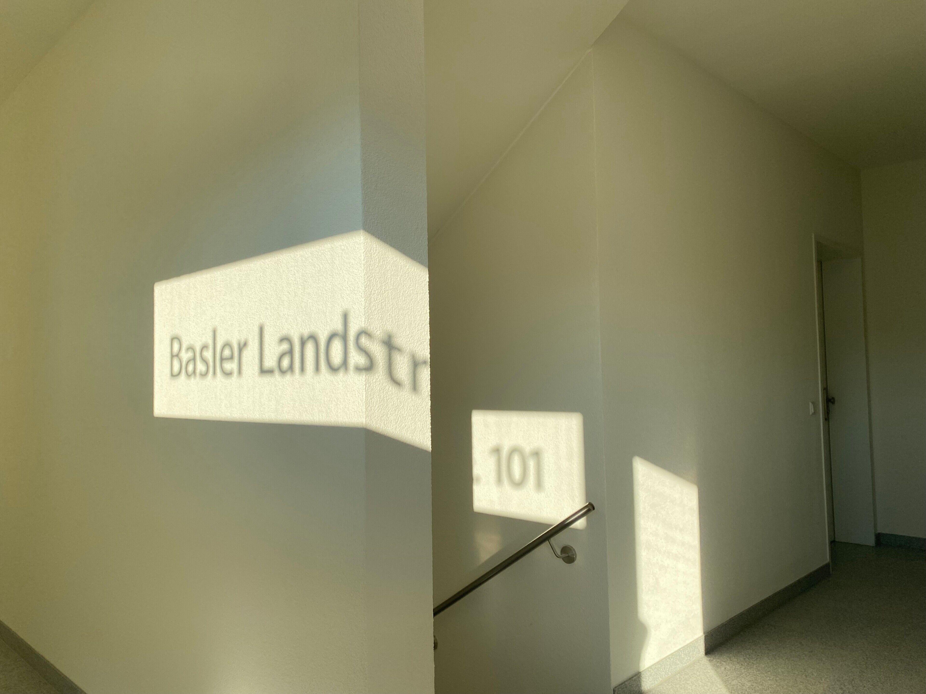 Ein Flur mit einem Schild mit der Aufschrift 'Basler Landstr.' und einem weiteren Schild mit der Nummer '101'.