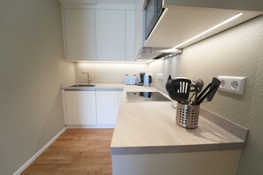 Una cocina compacta con armarios blancos, encimera de madera y un portalapapeles.