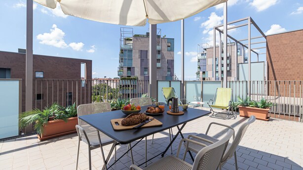 A rooftop terrace with a table set for breakfast, including bread, fruit, and a beverage. - Italianway Comfort - Vico Magistretti 1 A (Milano)
