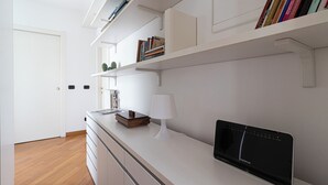A modern kitchen with white cabinetry, a built-in stove, and a countertop with a laptop and a lamp. - Italianway Comfort - Vico Magistretti 1 A (Milano)