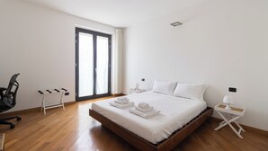 A bedroom with a wooden bed, white linens, a desk, and a chair. - Italianway Comfort - Vico Magistretti 1 A (Milano)