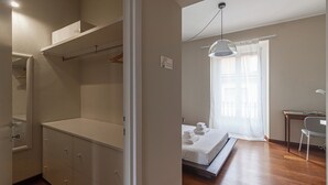 Une chambre à coucher avec un lit, un bureau et une chaise. On y trouve une armoire avec des tiroirs et une étagère.