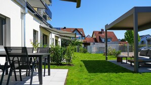 Um pátio com móveis de exterior, uma área de estar coberta e um gramado bem cuidado.