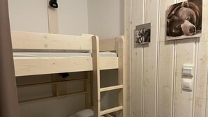 A bunk bed with a wooden frame and white bedding, a wall-mounted light, and a small framed picture of a dog. - 150m from ski slopes, 1st floor, swimming pool, tv, ski locker, 30m², Gourette (Eaux-Bonnes)