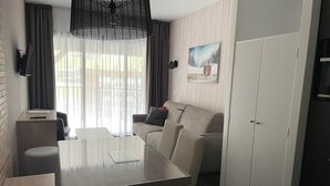 A modern hotel room with a dining table, sofa, and wardrobe. - 150m from ski slopes, 1st floor, swimming pool, tv, ski locker, 30m², Gourette (Eaux-Bonnes)