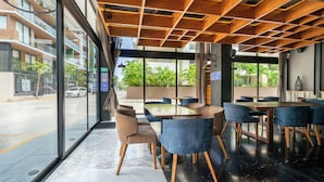 A modern interior with a wooden ceiling, large windows, and a seating area with tables and chairs. - 1 Br Condo with Rooftop Pool & Bar - IT (Playa del Carmen)