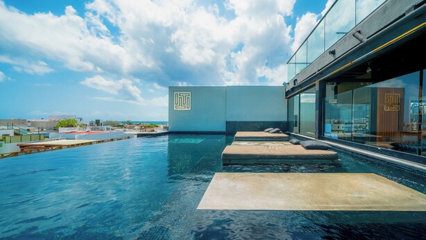 A rooftop infinity pool with a clear view of the sky and distant buildings. - 1 Br Condo with Rooftop Pool & Bar - IT (Playa del Carmen)