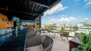 A rooftop bar with wicker furniture, a marble counter, and potted plants. - 1 Br Condo with Rooftop Pool & Bar - IT (Playa del Carmen)