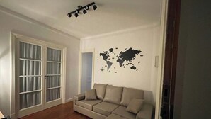 A living room with a sectional sofa, a world map wall decoration, and a ceiling light fixture. - Luxury apartment in Recoleta. (Buenos Aires)