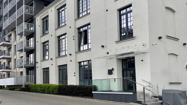A multi-story residential building with balconies, large windows, and a gated entrance. - A Comfortable Apartment in the Heart of the City (Łódź)