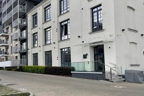 A multi-story residential building with balconies, large windows, and a gated entrance. - A Comfortable Apartment in the Heart of the City (Łódź)