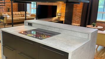 A modern kitchen with a built-in stove, dark cabinetry, and a large window providing natural light.