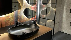 A modern bathroom with a large oval sink, a mirror, and a unique wall design. - A Comfortable Apartment in the Heart of the City (Łódź)