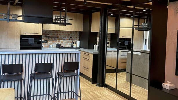 Uma cozinha moderna com área de bar, piso de madeira e uma janela grande.