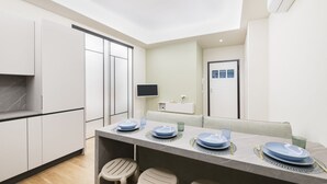 A modern kitchen with a dining area. It includes a kitchen counter, a dining table set with plates and glasses, and a sofa in the dining area.