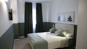 A bedroom with a bed, a nightstand, a wall-mounted TV, and a painting.