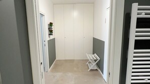 A hallway with a white door leading to a room with a white wardrobe and a radiator.
