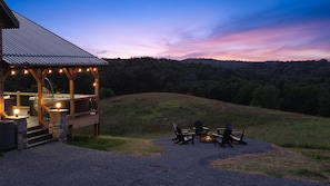 A wooden deck with outdoor seating and a hot tub, overlooking a forested hillside. - The View at Grizzly Mountain | Hocking Hills, Pool (Creola)