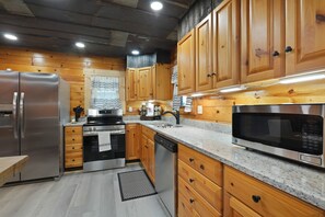 A modern kitchen with wooden cabinets, stainless steel appliances, and granite countertops.