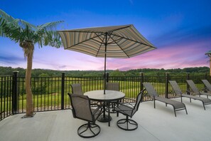 An outdoor patio with a round table, chairs, and a large umbrella. - The View at Grizzly Mountain | Hocking Hills, Pool (Creola)