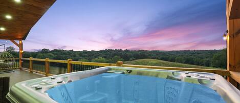 A hot tub on a wooden deck with a view of a forested landscape.