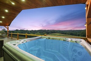 Ein Whirlpool auf einer Holzterrasse mit Blick auf eine bewaldete Landschaft.