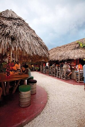 Un espace extérieur aménagé pour les repas, avec des parasols en chaume et des tabourets en bois.