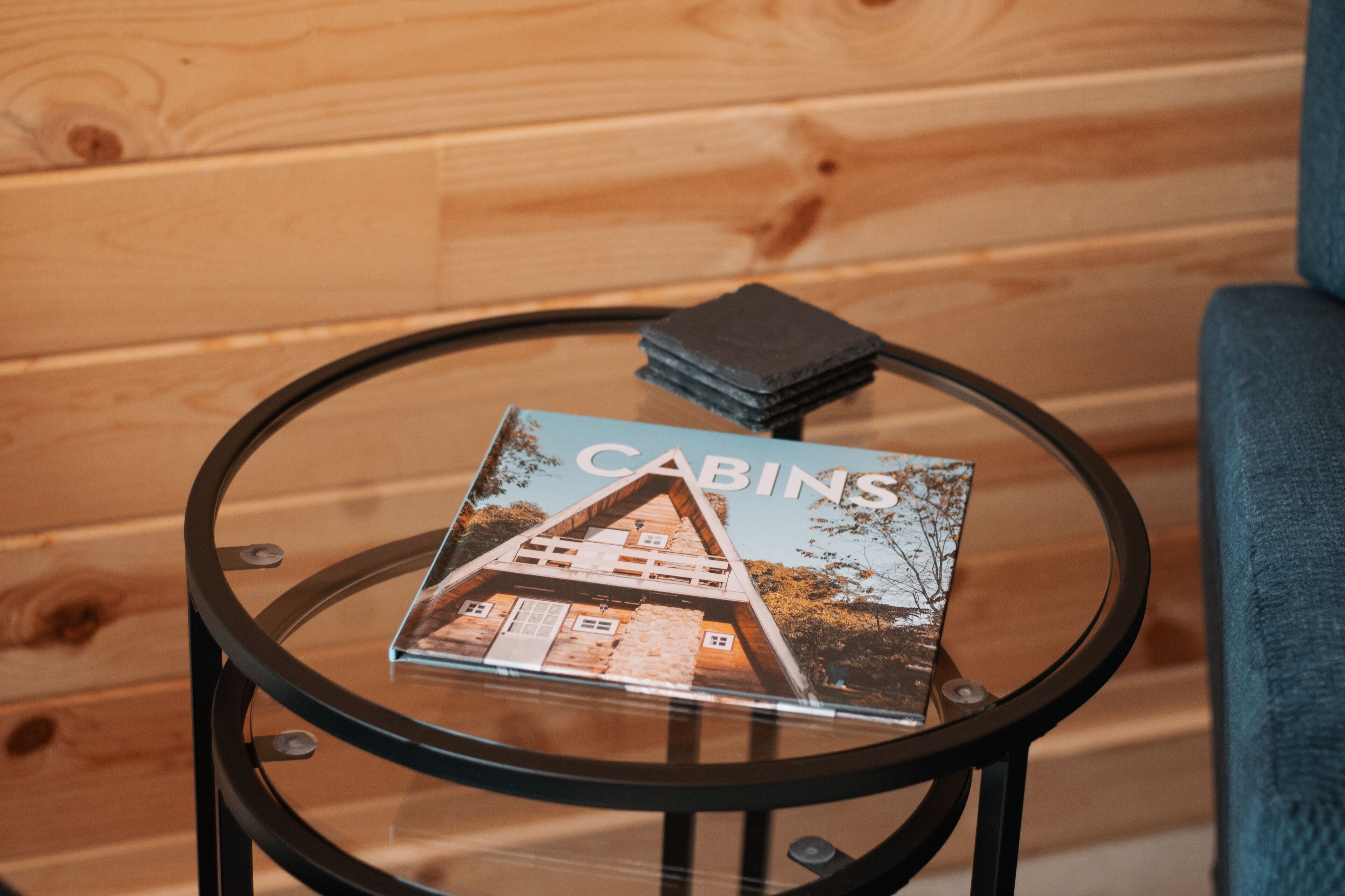 Ein Glastisch mit einer Zeitschrift namens "CABINS" und einer Geldbörse, vor einer Holzwand.