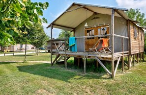 A wooden cabin with a balcony, a covered porch, and a hanging light fixture.