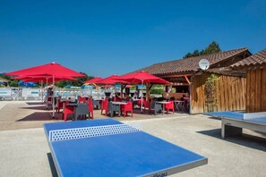 An outdoor seating area with red umbrellas, tables, and chairs.