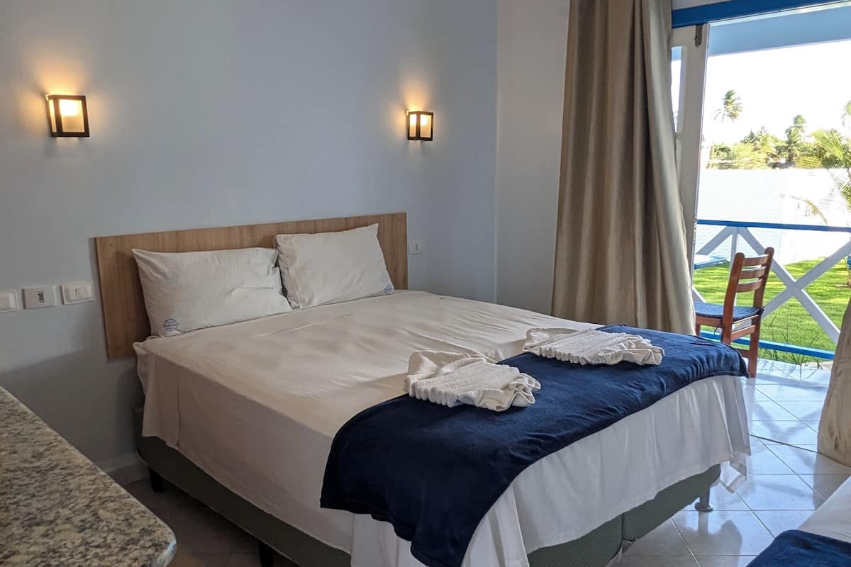 Ein Hotelzimmer mit Bett, einem kleinen Tisch und Blick ins Freie.