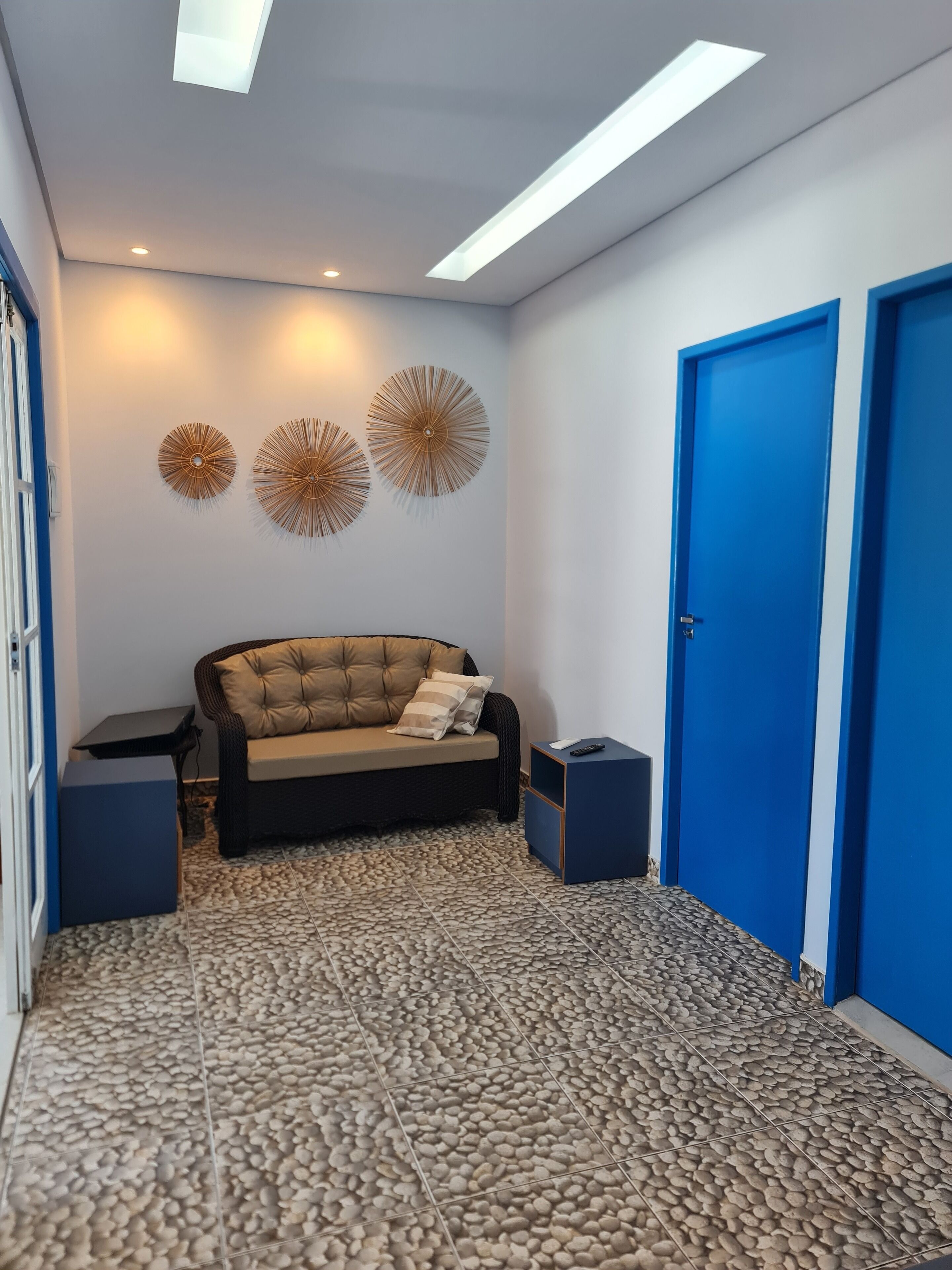 Quarto moderno com sofá, uma mesinha e porta azul.