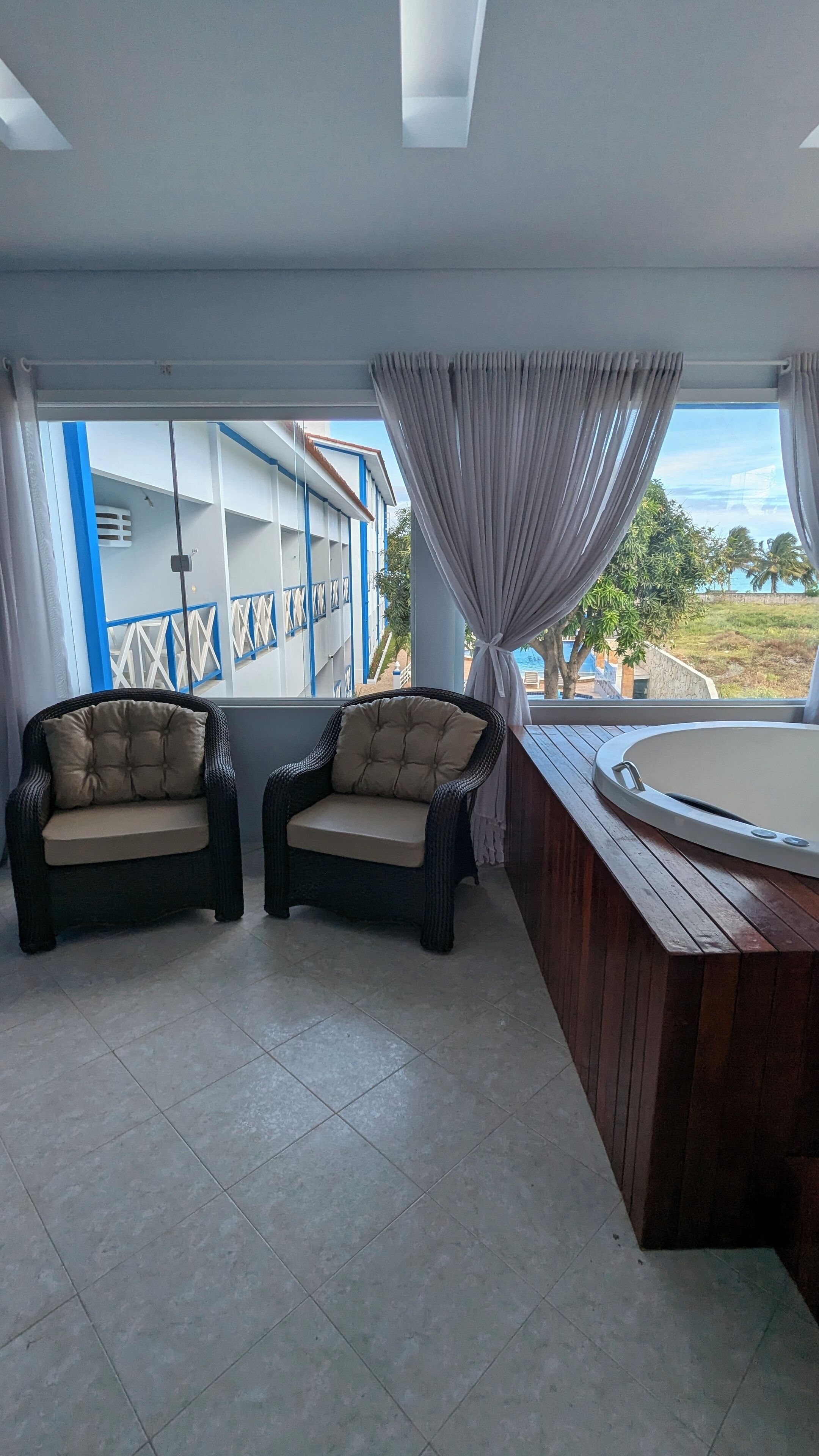 Una habitación con dos sillas de mimbre, un banco de madera y un jacuzzi.