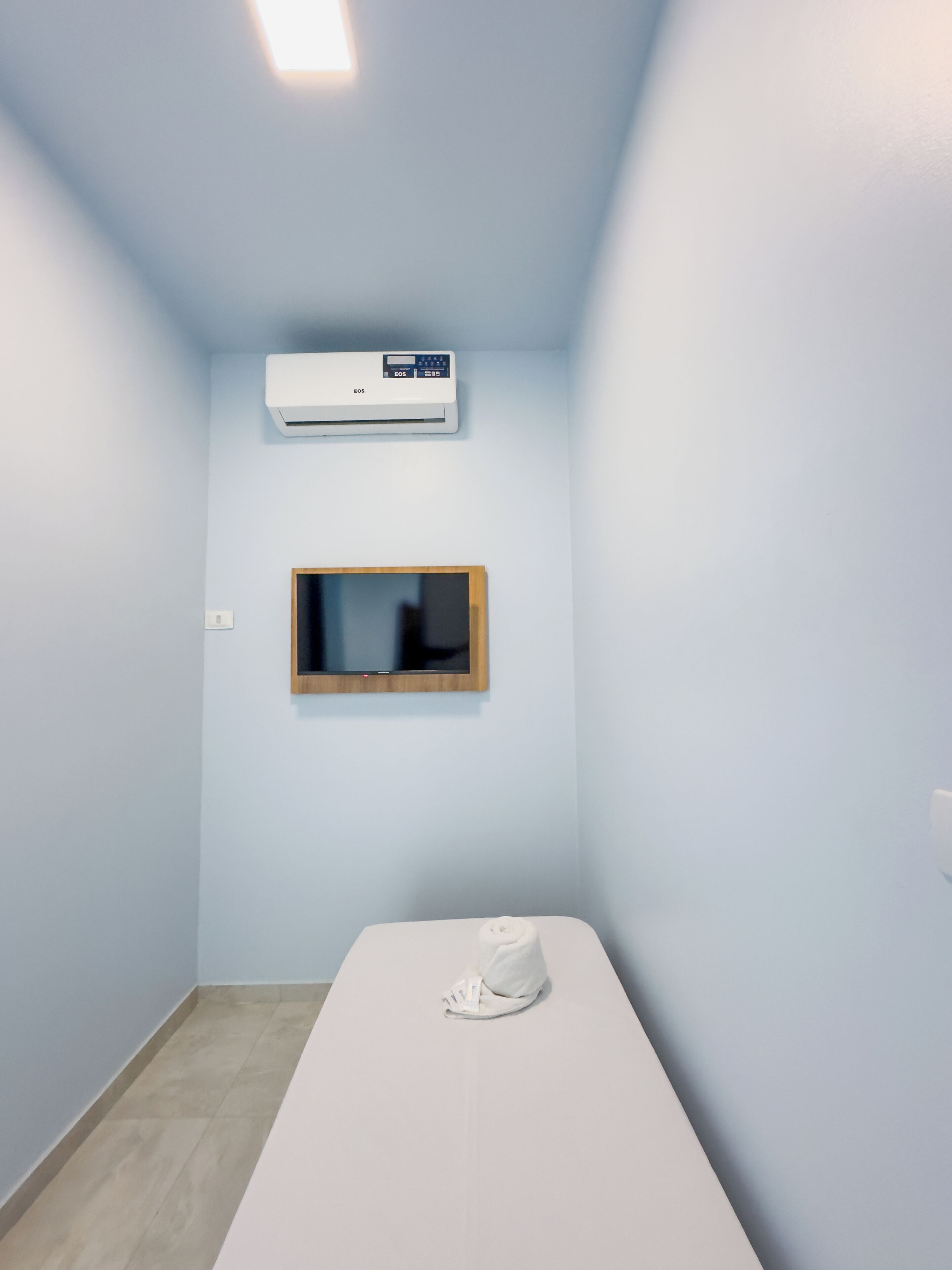 Une pièce avec un lit, un climatiseur fixé au mur et une petite fenêtre.