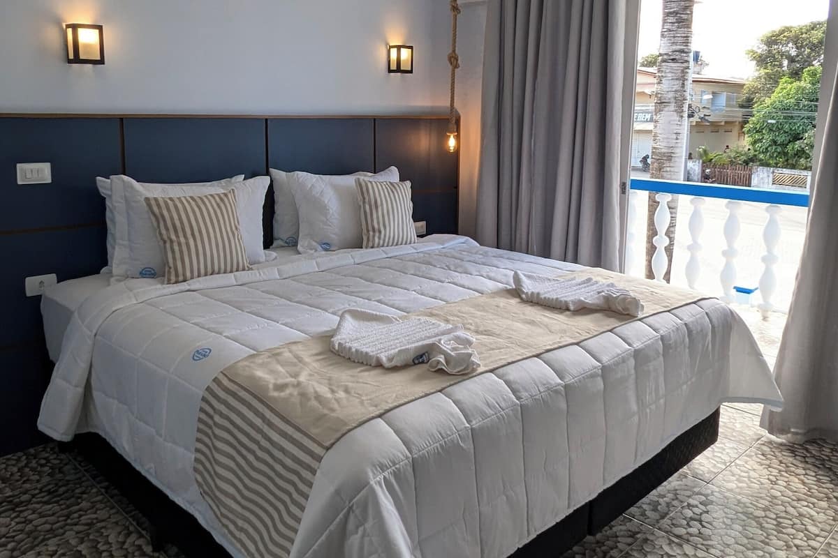 Ein geräumiges Schlafzimmer mit einem großen Bett, Blick ins Freie und einem außergewöhnlichen Deckenstil.