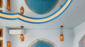 Een moderne hotelkamer met een groot bed, een ronde spiegel boven het bed en een klein tafeltje met een lamp.